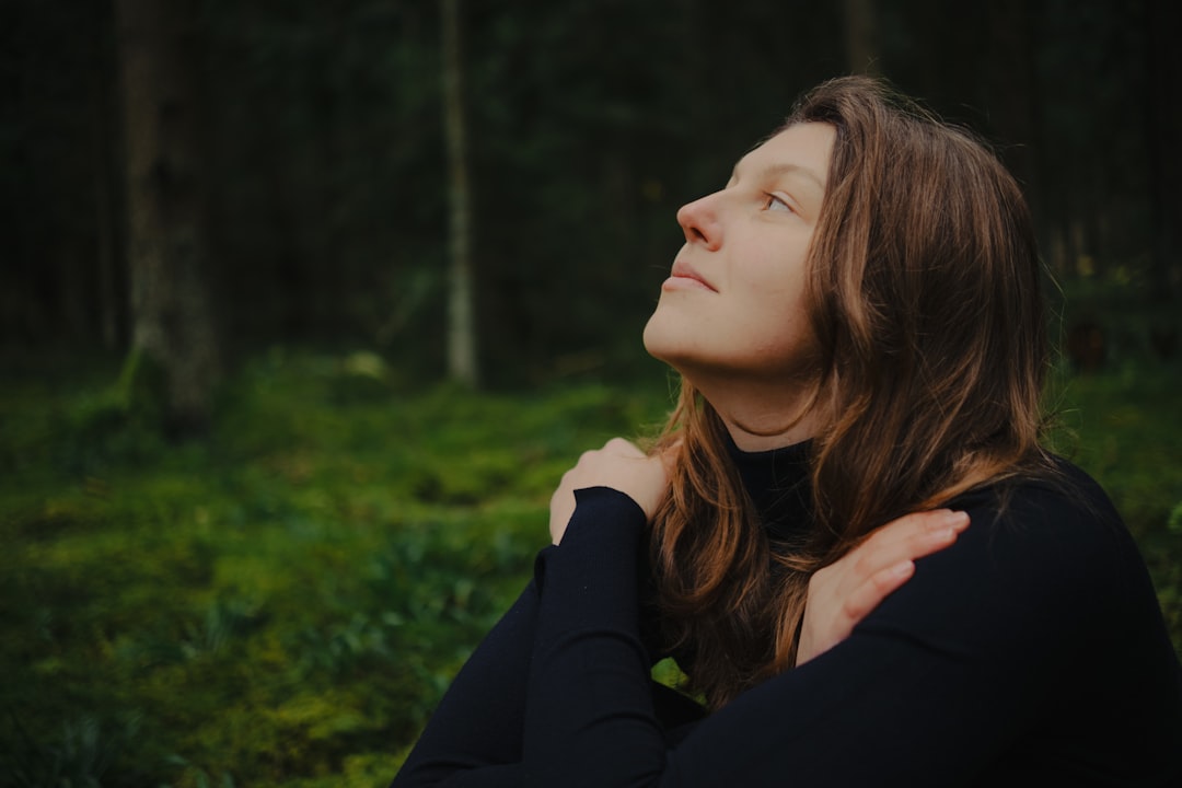 Woman with eyes closed embracing herself in forest