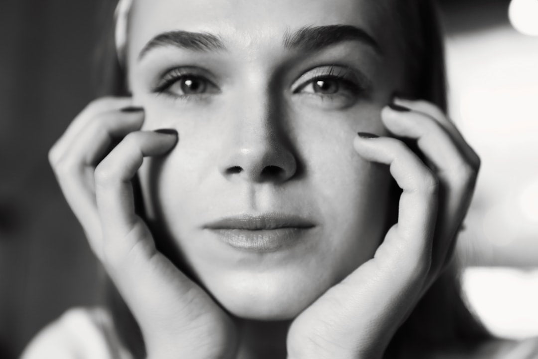 a black and white photo of a woman holding her hands to her face