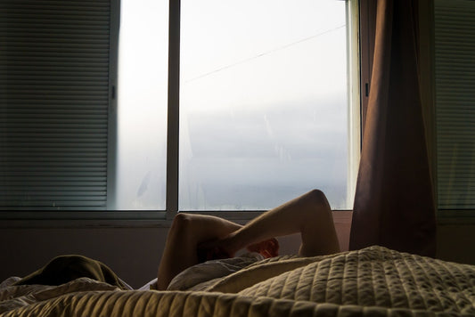 Person relaxing in bed with a window.