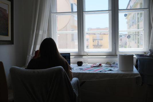 Person works near a bright window in a room.