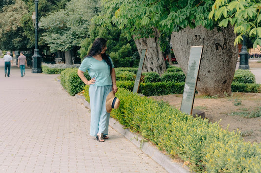 Woman in light blue clothing standing on a park path