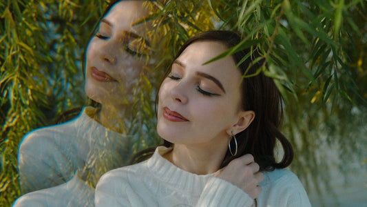 Young woman with eyes closed under green leaves