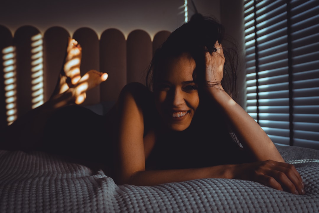 Smiling woman lying on bed with striped shadows