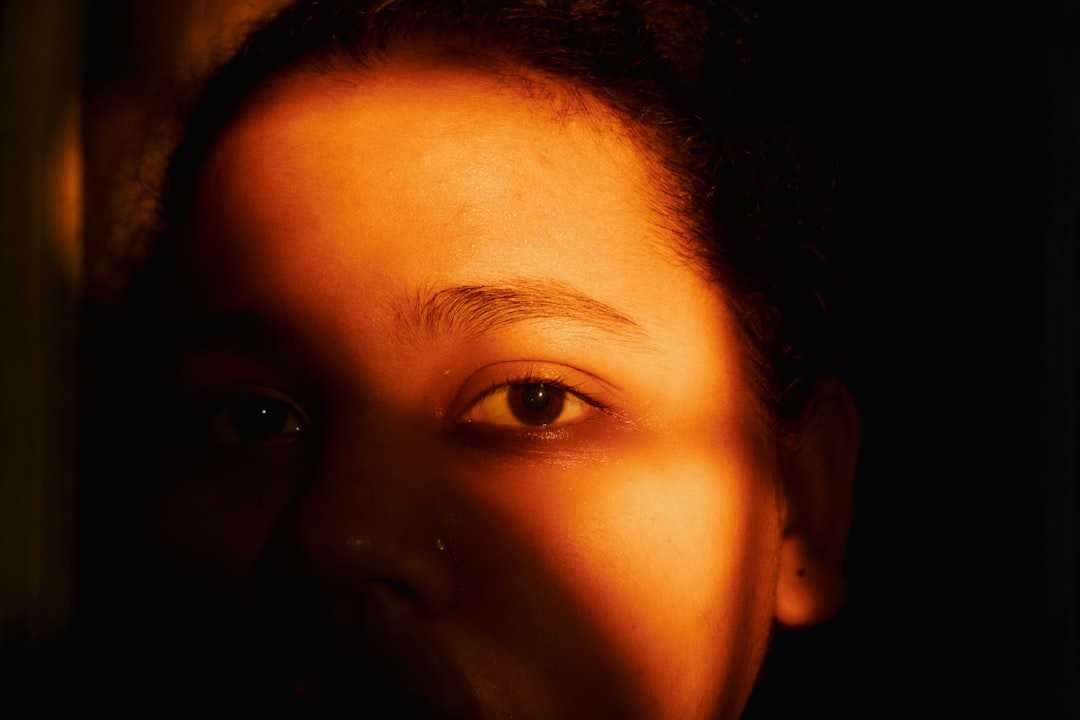 Warm lighting illuminates a person's face in the dark.